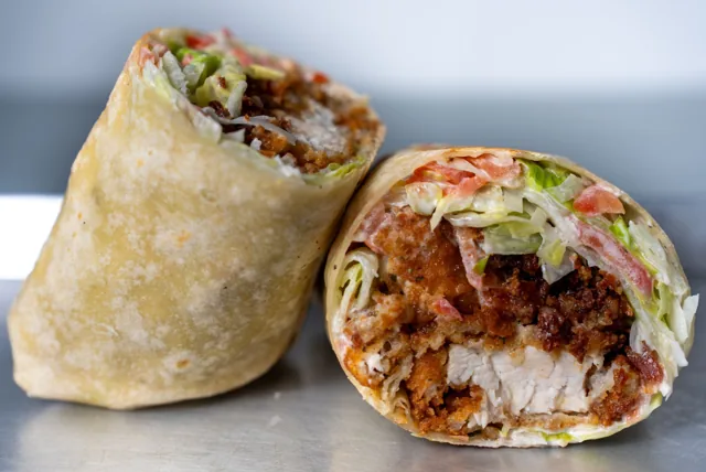 A cut chicken wrap filled with tomato, bacon, lettuce and cheese