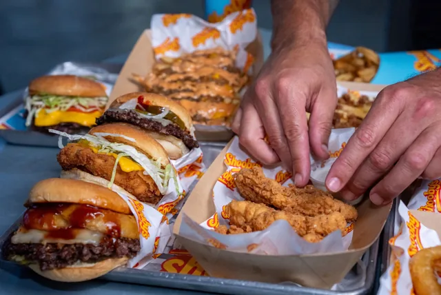 Reaching for golden chicken tenders in a spread of Shooby’s burgers and sides