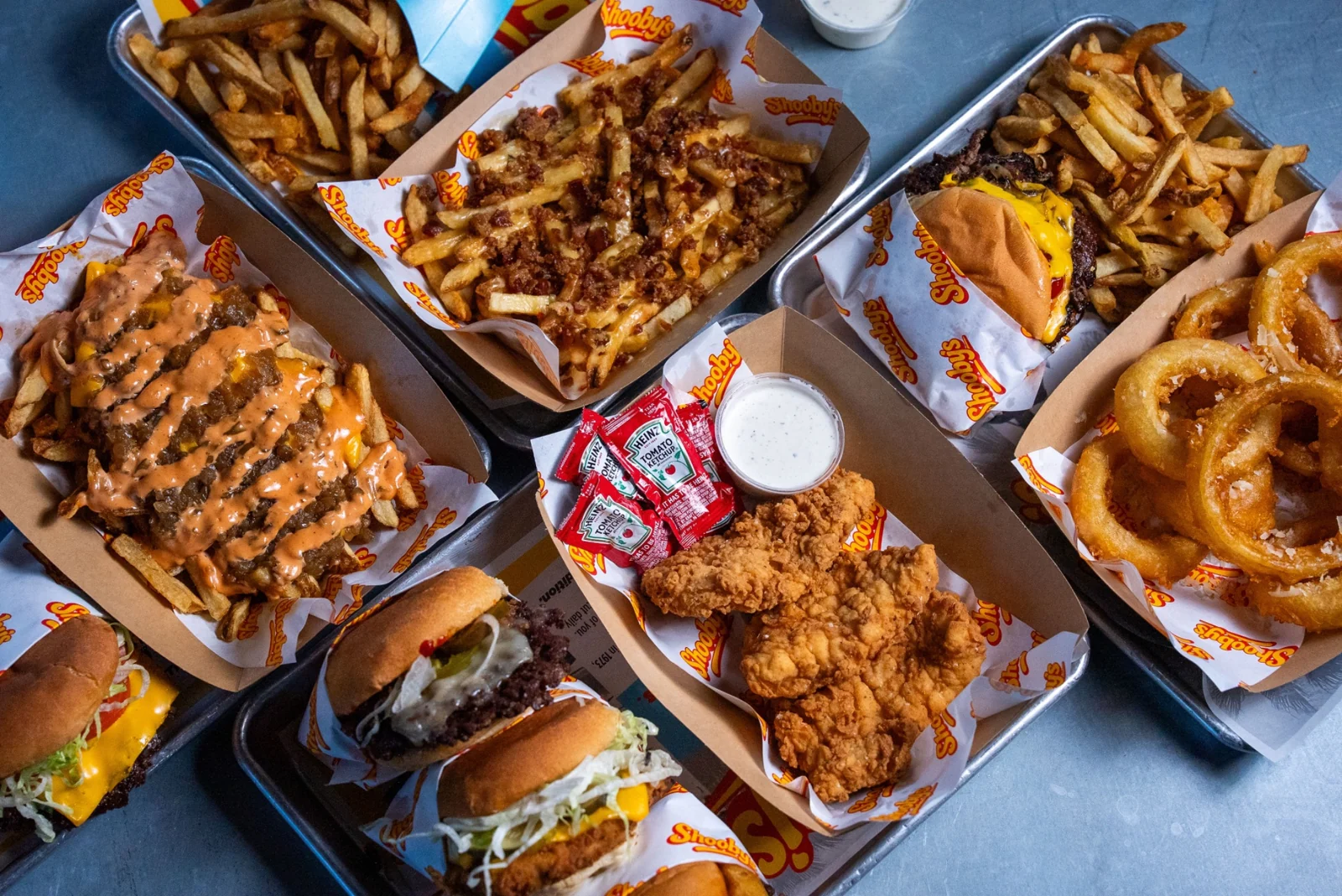 A generous spread of burgers, loaded fries, onion rings and chicken tenders ready for a crowd
