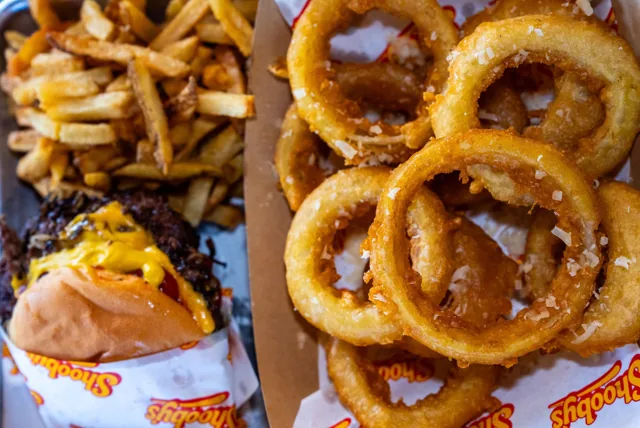 Golden onion rings beside a burger and hand-cut fries