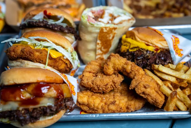 A generous pile of crispy chicken tenders beside burgers, wraps and fries