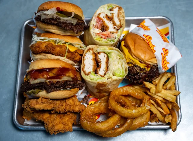 An overhead tray of burgers, chicken sandwiches, wraps, fries and onion rings