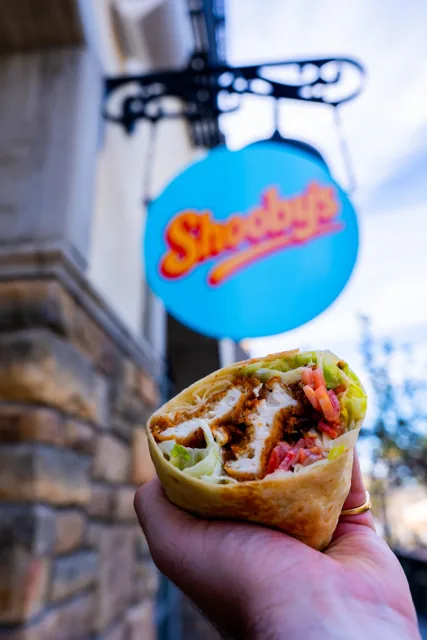 A chicken wrap held beneath the Shooby’s storefront sign