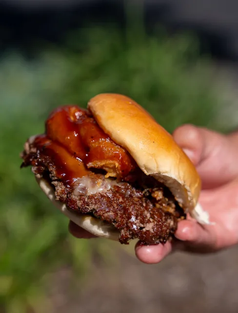 A burger stacked with bacon, beef and melted cheese